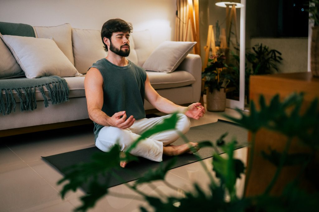 Muškarac sjedi i prakticira vizualizaciju u sobi
